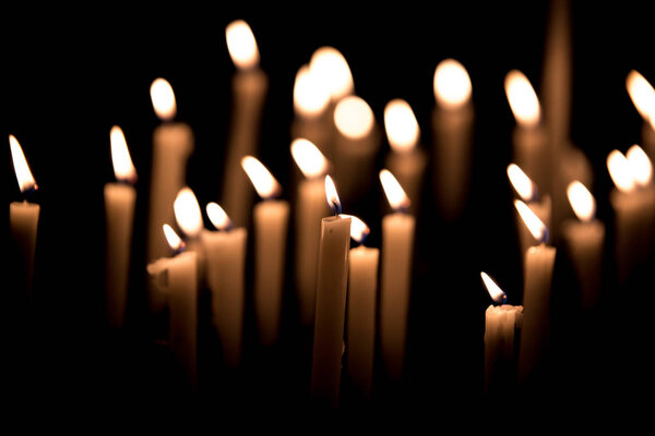 Many burning candles - Light of candles in the church on the black background