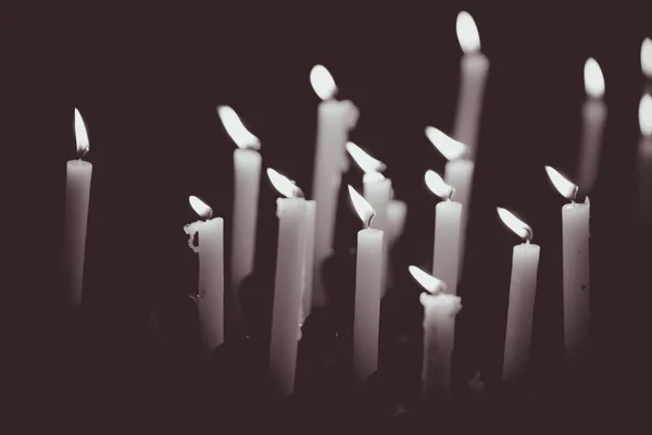 Many burning candles - Light of candles in the church on the black background