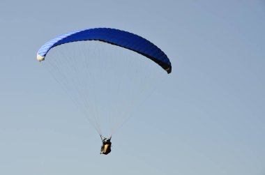 Yamaçparaşütü bulutlar arka planı mavi gökyüzünde uçuyor. Güneşli bir havada yamaç paraşütü. Aşırı spor ve eğlence