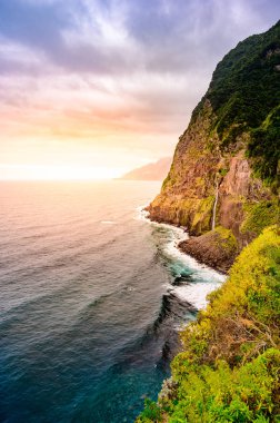 Madeira Adası'ndaki Ponta do Poiso'da Gelin Peçe Şelalesi (Veu da noiva) ile güzel vahşi sahil manzarası. Porto Moniz yakınında, Seixal, Portekiz.