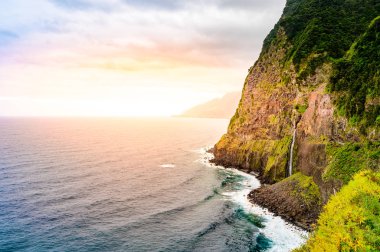 Madeira Adası'ndaki Ponta do Poiso'da Gelin Peçe Şelalesi (Veu da noiva) ile güzel vahşi sahil manzarası. Porto Moniz yakınında, Seixal, Portekiz.