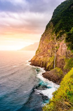 Madeira Adası'ndaki Ponta do Poiso'da Gelin Peçe Şelalesi (Veu da noiva) ile güzel vahşi sahil manzarası. Porto Moniz yakınında, Seixal, Portekiz.