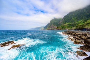 Madeira Adası'ndaki Ponta do Poiso'da Gelin Peçe Şelalesi (Veu da noiva) ile güzel vahşi sahil manzarası. Porto Moniz yakınında, Seixal, Portekiz'den görünüm.