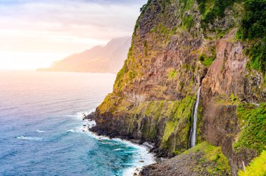 Madeira Adası'ndaki Ponta do Poiso'da Gelin Peçe Şelalesi (Veu da noiva) ile güzel vahşi sahil manzarası. Porto Moniz yakınında, Seixal, Portekiz.