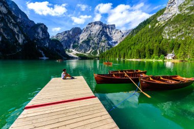 Güzel dağ manzarasında Pragser Wildsee olarak da bilinen Braies Gölü'ndeki İskele'de dinlenen kadın. Dolomites, Güney Tirol, İtalya, Avrupa'da Amazing Seyahat hedef Lago di Braies.