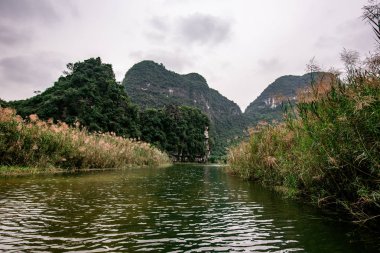 Trang Bir Manzara karst kuleleri ve nehir boyunca bitkiler (Unesco Dünya Mirası) tarafından oluşturulan Tekne mağara turu. Vietnam topraklarındaki Halong Körfezi. Ninh Binh province, Vietnam.