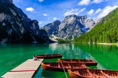 Güzel dağ manzarasında Pragser Wildsee olarak da bilinen Braies Gölü'ndeki İskele'de dinlenen kadın. Dolomites, Güney Tirol, İtalya, Avrupa'da Amazing Seyahat hedef Lago di Braies.