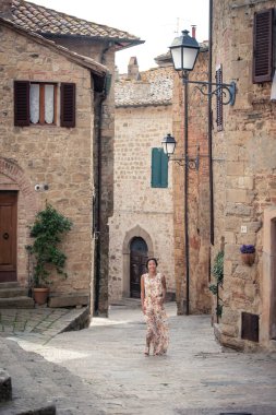 Genç asyalı kız yaz günü Monticchiello kasabasında yürüyor. Geleneksel eski taş evler ile Amazing gezinti - Toskana, İtalya, Avrupa
