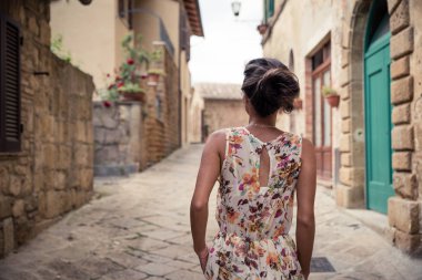 Genç asyalı kız yaz günü Monticchiello kasabasında yürüyor. Geleneksel eski taş evler ile Amazing gezinti - Toskana, İtalya, Avrupa