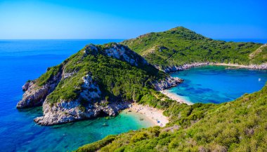 Porto Timoni 'nin Afionas plajı, Korfu, İyon adası, Yunanistan ve Avrupa' da kristal berrak gök mavisi suyu bulunan bir cennet çifte kumsalı.