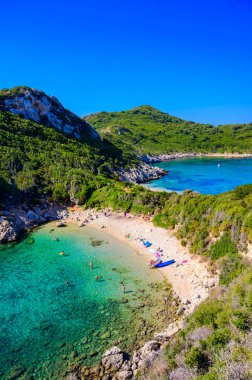 Porto Timoni 'nin Afionas plajı, Korfu, İyon adası, Yunanistan ve Avrupa' da kristal berrak gök mavisi suyu bulunan bir cennet çifte kumsalı.