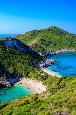 Porto Timoni 'nin Afionas plajı, Korfu, İyon adası, Yunanistan ve Avrupa' da kristal berrak gök mavisi suyu bulunan bir cennet çifte kumsalı.