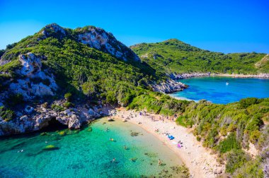 Porto Timoni 'nin Afionas plajı, Korfu, İyon adası, Yunanistan ve Avrupa' da kristal berrak gök mavisi suyu bulunan bir cennet çifte kumsalı.