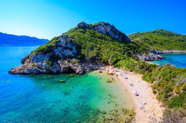 Porto Timoni 'nin Afionas plajı, Korfu, İyon adası, Yunanistan ve Avrupa' da kristal berrak gök mavisi suyu bulunan bir cennet çifte kumsalı.
