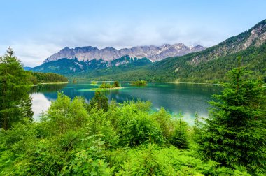 Eibsee Gölü 'nün ortasında Zugspitze Dağı' yla çam ağaçları olan küçük adalar. Cennet plajlı güzel manzara ve Alman Alpleri, Bavyera, Almanya, Avrupa 'daki berrak mavi su.