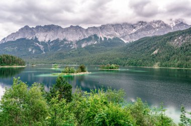 Eibsee Gölü 'nün ortasında Zugspitze Dağı' yla çam ağaçları olan küçük adalar. Cennet plajlı güzel manzara ve Alman Alpleri, Bavyera, Almanya, Avrupa 'daki berrak mavi su.