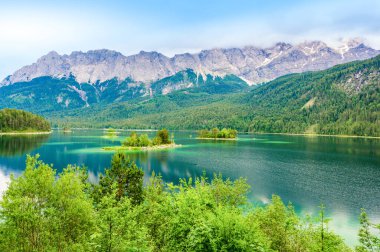 Eibsee Gölü 'nün ortasında Zugspitze Dağı' yla çam ağaçları olan küçük adalar. Cennet plajlı güzel manzara ve Alman Alpleri, Bavyera, Almanya, Avrupa 'daki berrak mavi su.