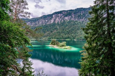 Eibsee Gölü 'nün ortasında Zugspitze Dağı' yla çam ağaçları olan küçük adalar. Cennet plajlı güzel manzara ve Alman Alpleri, Bavyera, Almanya, Avrupa 'daki berrak mavi su.