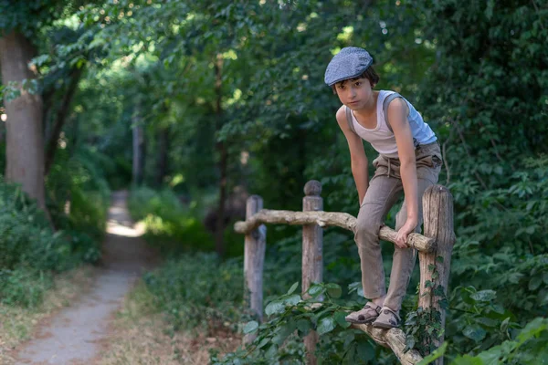 サスペンダーと木製のフェンス近くのノースリーブのシャツとパンツに身を包んだ少年のポートレート — ストック写真
