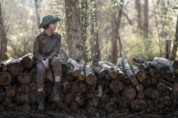 Boy Coveralls Hat Sitting Pile Sawn Logs Forest — Stock Photo, Image