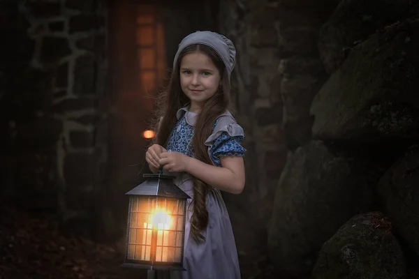 一个穿着复古衣服的女孩站在堡垒墙边 带着灯笼 — 图库照片
