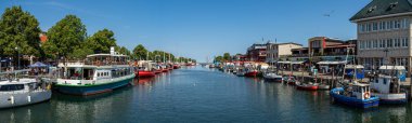 WARNEMUENDE (ROSTOCK), GERMANY - JULY 25, 2019: Panoramic view of the berths for ships and the historic quarter of Rostock - Warnemuende. clipart