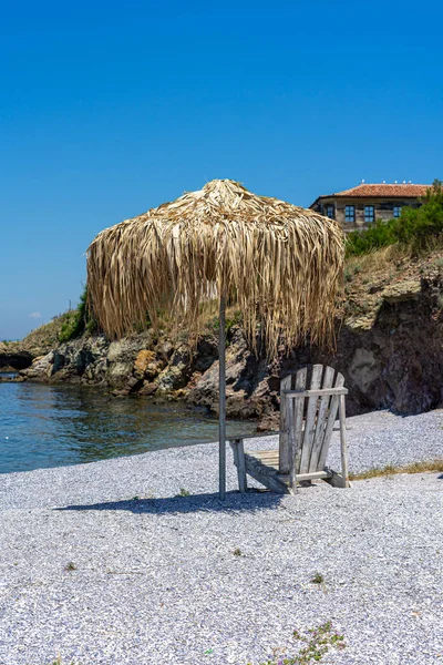 Strandstoel Een Paraplu Gemaakt Van Stro Een Stenige Strand Zomer — Stockfoto