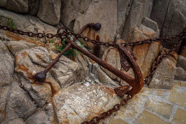 花崗岩の石の鎖を持つ古い錆びたアンカー ストックフォト