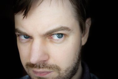 Koyu arka plan üzerinde şüpheli yüzü olan adam.