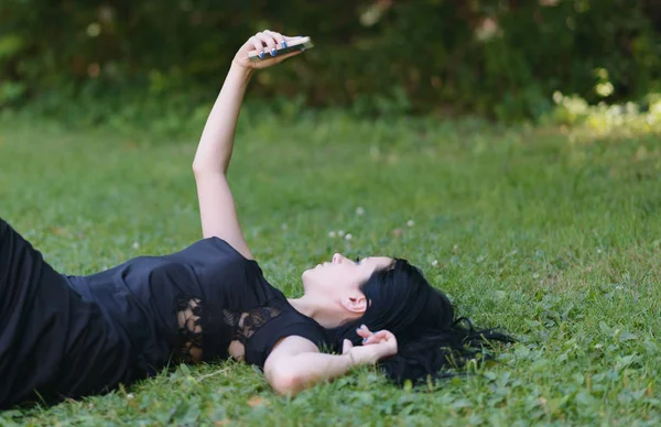 Молодая Женщина Делает Селфи Своем Смартфоне Лежа Зеленой Траве Селективный — стоковое фото