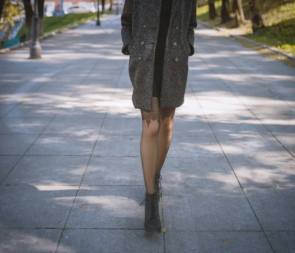 Legs of woman in coat autumn at street.