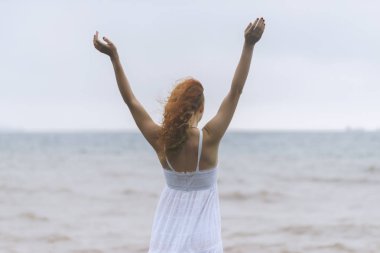 Genç Kızıl saçlı kadının elleri sahilde sisli gün içinde yayıldı..