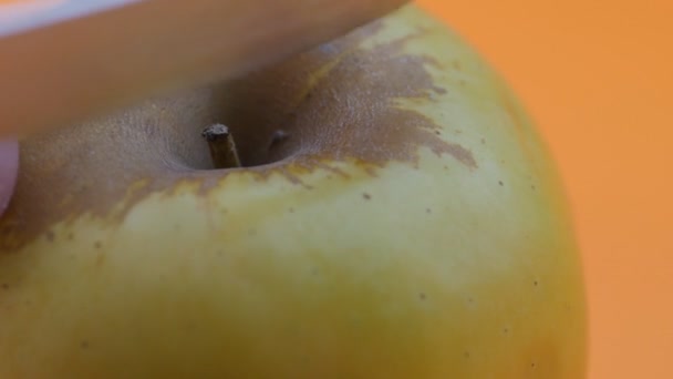 Χέρι Κόβει Ένα Μήλο Ένα Μαχαίρι Πορτοκαλί Φόντο Αργή Κίνηση — Αρχείο Βίντεο