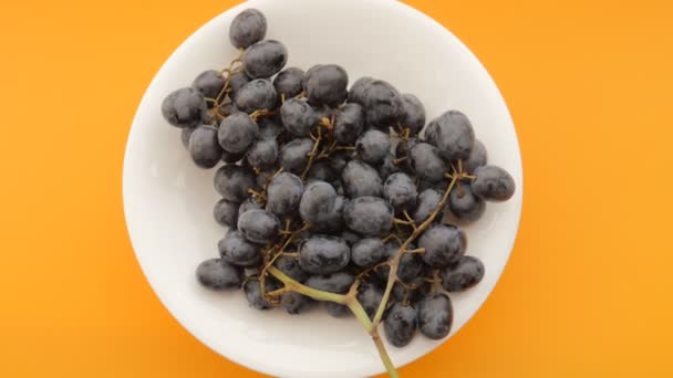 Dark Grapes Plate Rotating Orange Background Top View — Stock Video