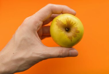 Elma portakal arka plan üzerinde elinde. Seçici odak alan sığ derinliği ile.