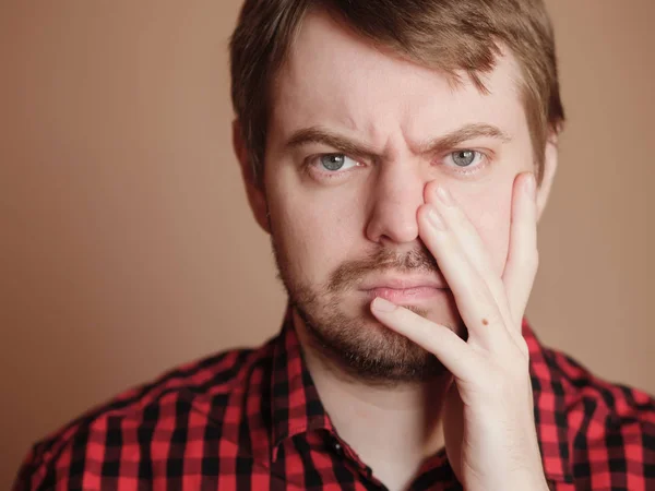 Sad young man, portrait on the beige background.