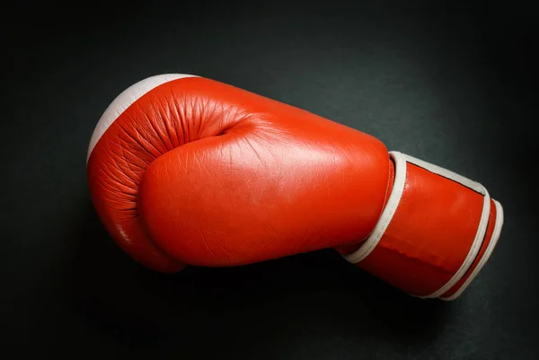 Old and used boxing glove on dark background.