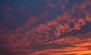 Turuncu renkli bulutlarla dramatik günbatımı gökyüzü.