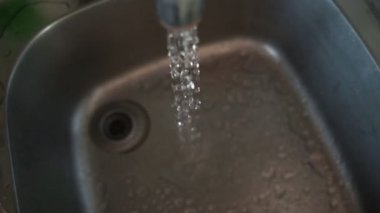Yavaş çekimde bir mutfak lavabo deliği aşağı akan su. Seçici odak.