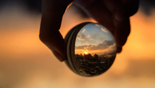Handen Håller Glasboll Som Reflekterar Solnedgången Himmel Över Staden — Stockfoto