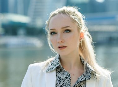 Açık havada beyaz ceketli genç kadın portresi.