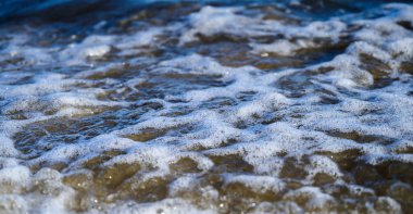 Gün batımında deniz kıyısında dalgalar. Sığ alan derinliğine sahip seçici odak.