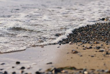 Gün batımında deniz kıyısında dalgalar. Sığ alan derinliğine sahip seçici odak.