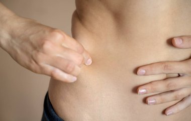 Genç, formda bir kadın kendi tarafında yağ kontrolü yapıyor. Vücut bakımı kavramı.