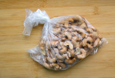 Tahta masadaki plastik poşette kaju fıstığı..