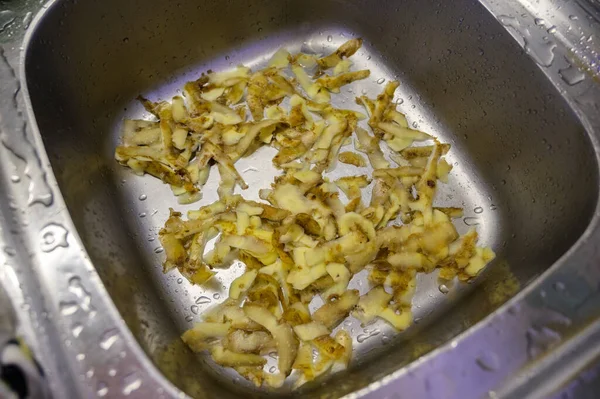 Potato peeling in the metal sink.