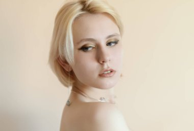 Bej bir duvara karşı poz vermiş zarif bir genç bayan..