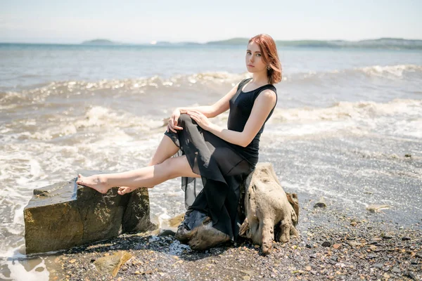 Jovem Mulher Vestido Preto Sentado Areia Gosta Mar — Fotografia de Stock