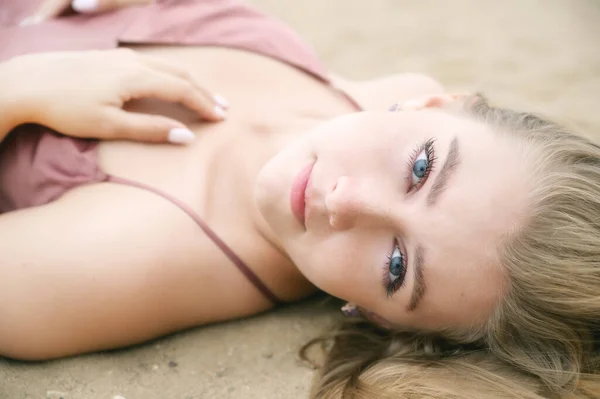 身穿粉色衣服的年轻女子躺在沙滩上享受大海 — 图库照片