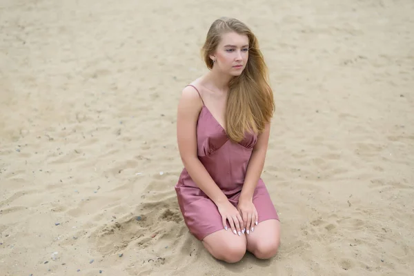 Pembe Elbiseli Genç Kadın Kumda Oturuyor Denizin Tadını Çıkarıyor — Stok fotoğraf